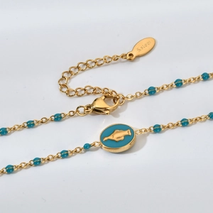 Détail du collier en acier inoxydable doré avec pendentif œil émaillé bleu et fermoir
