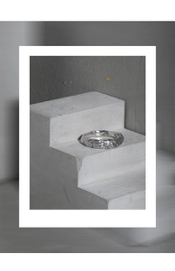 Macro shot of silver ring with irregular lava texture and inlaid zircon on concrete base