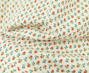 Detail van bloemenstof met rode bessenprint en fijne dubbele stiksels op de zoom