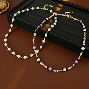 Detail of beaded pearl necklaces with green and purple crystals on jewelry tray
