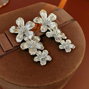Detailed close-up of vintage silver flower tassel earrings on a brown velvet box