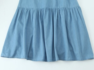 Détail d'une robe midi en jean bleu clair avec ourlet plissé et coutures précises