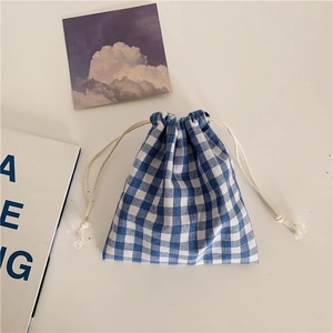 Close-up of blue gingham cotton linen drawstring bag with white rope on white desk