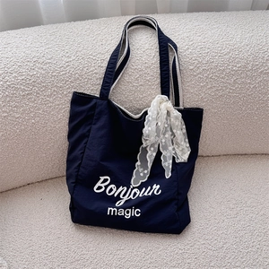 Detail of navy canvas tote bag featuring Bonjour magic print and floral silk scarf accessory