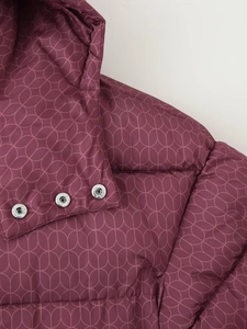Détail de boutons-pression argentés sur manteau violet à motif géométrique circulaire
