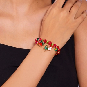 Detailed close-up of red Christmas bracelet with reindeer and bell charms worn on wrist