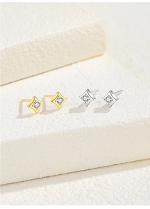 Macro view of gold and silver star earrings with clear zircon on a minimalist background