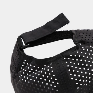 Detail of laser-cut mesh holes and adjustable rear strap on a black baseball cap