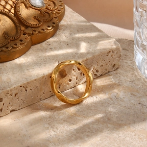 Detail of twisted 18K gold plated wave ring on beige stone with artistic shadows