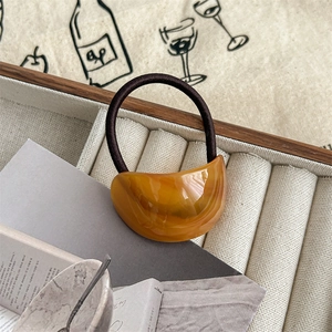 Close-up of amber resin crescent hair tie with durable brown elastic in a jewelry box