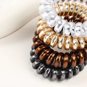 Macro detail of elastic spiral hair ties in transparent gold and metallic tones