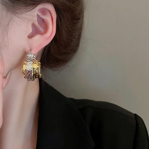Close-up of mixed metal hammered texture earrings with gold and silver interlock detail
