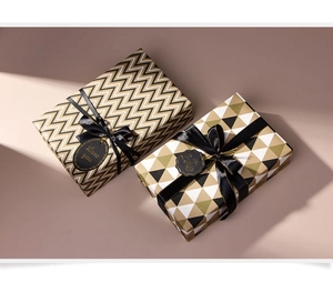 Detail of luxury gold and black geometric gift wrap with silk ribbon and tags