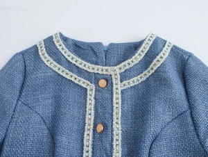 Nahaufnahme des blauen Tweed-Ausschnitts mit geflochtenem Besatz und Goldknöpfen