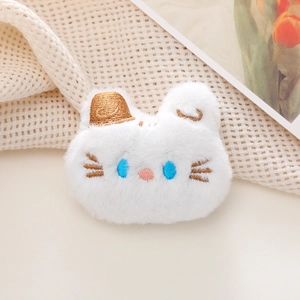 Close-up of a plush white cartoon animal brooch with blue eyes and embroidery detail