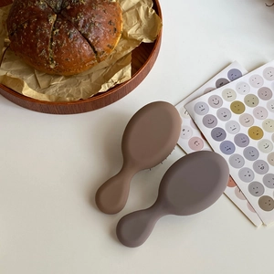 Dettaglio delle mini spazzole per capelli massaggianti in marrone e lavanda