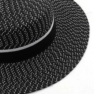 Macro detail of black and white woven texture and striped ribbon on the straw flat top hat
