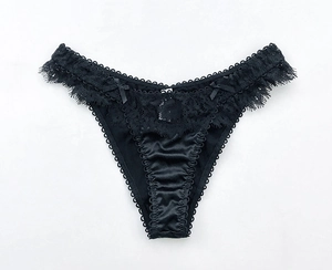 Dettaglio di mutandine in pizzo nero con inserti in raso e due piccoli fiocchi decorativi