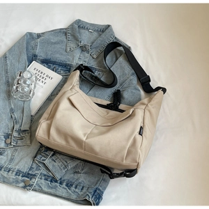 Detailed top view of a casual beige tote bag styled with denim and books for a fashion look