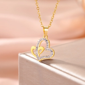 Detail shot of golden double heart pendant with sparkling white crystals on soft satin