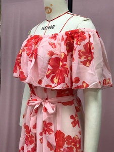 Detail eines rosa Maxikleids mit Blumenmuster, Rüschen-Ausschnitt und Taillengürtel