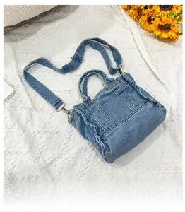 Detail of blue washed denim tote bag featuring ruffled edges and removable shoulder strap