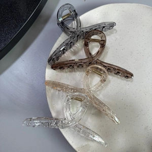 Detailed top view of four large 13cm glossy hair claws in gray and beige on a plate