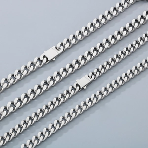 Detailed view of polished stainless steel silver Cuban links arranged on a gray surface