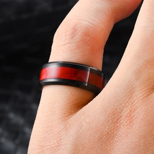 Close-up of black titanium steel men's ring with a striking red inlay on finger