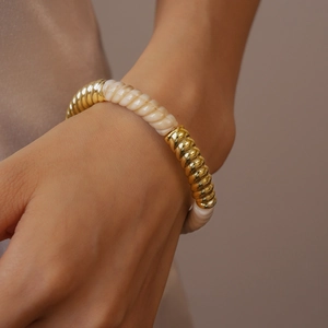 Gros plan d'un bracelet torsadé en acrylique vintage avec segments dorés au poignet