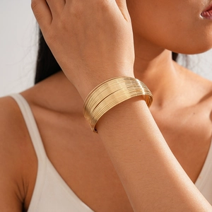 Detailed view of wide gold multi-layered wire cuff bracelet on female model wrist