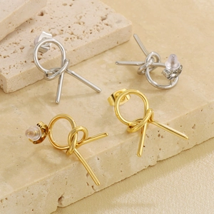 Detail of knotted geometric stud earrings in gold and silver on a silk background