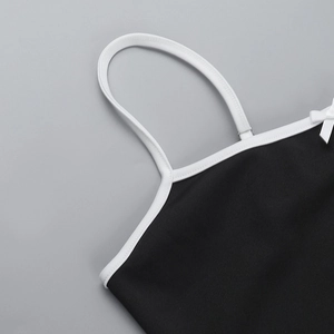 Detailansicht des schwarzen Trägerkleides mit weißen Schultergurten und Schleifendetail