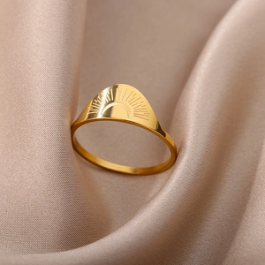 Detailed view of 18K gold plated stainless steel sun engraved ring on silk fabric