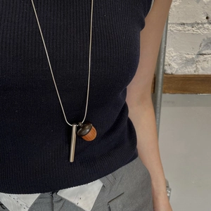 Detail of wooden acorn and silver cylinder pendant on a long snake chain necklace