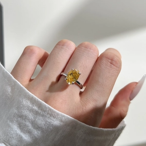 Detailed view of an oval yellow gemstone set in a polished silver four-prong ring