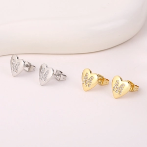 Gedetailleerde close-up van hartvormige letter M strass oorknopjes in goud en zilver.