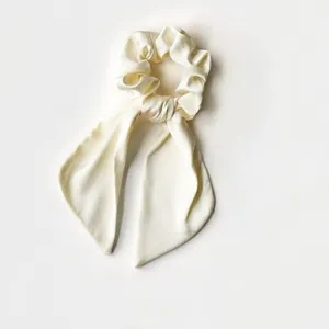 Elegant ivory satin silk scrunchie with long ribbon streamers shown on a neutral background