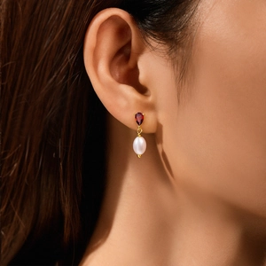 Close-up of S925 silver earrings with ruby-toned charms and white oval pearls