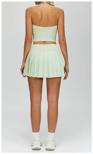 Rear view of light green halter backless top and pleated mini skirt athletic set