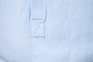 Macro detail of light blue cotton linen shirt showing stitching and fabric texture