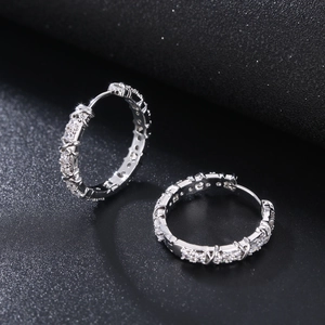 Silver hoop earrings with micro-pave cubic zirconia on a black textured surface