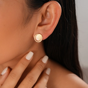 Boucle d'oreille ronde dorée avec incrustation de nacre, portée par un mannequin