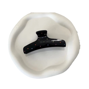 Elegant black acetate shark hair claw clip with colorful inlaid gems on white tray