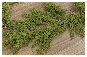 Macro shot of realistic green pine needle garland on a natural wood surface decor