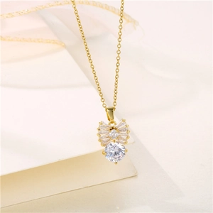 Elegant gold bow necklace with sparkling zircon pendant on a minimalist paper background