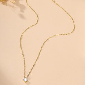 Detail of single round cubic zirconia pendant on thin gold chain with four-prong setting