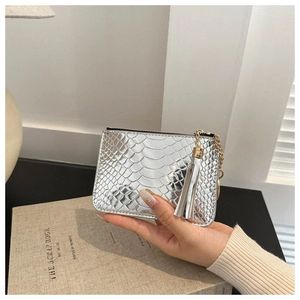 Detail of silver crocodile pattern coin purse with gold zipper and tassel on a book