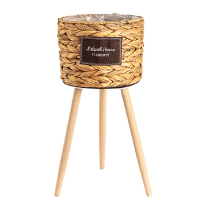 Handwoven flower pot with three wooden legs and Natural Home label on white background