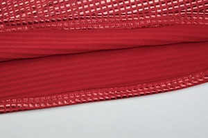 Détail d'une robe en maille côtelée rouge avec bordure dorée métallisée sur l'ourlet
